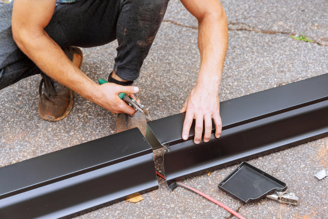 Installer cutting an aluminum gutter to size.